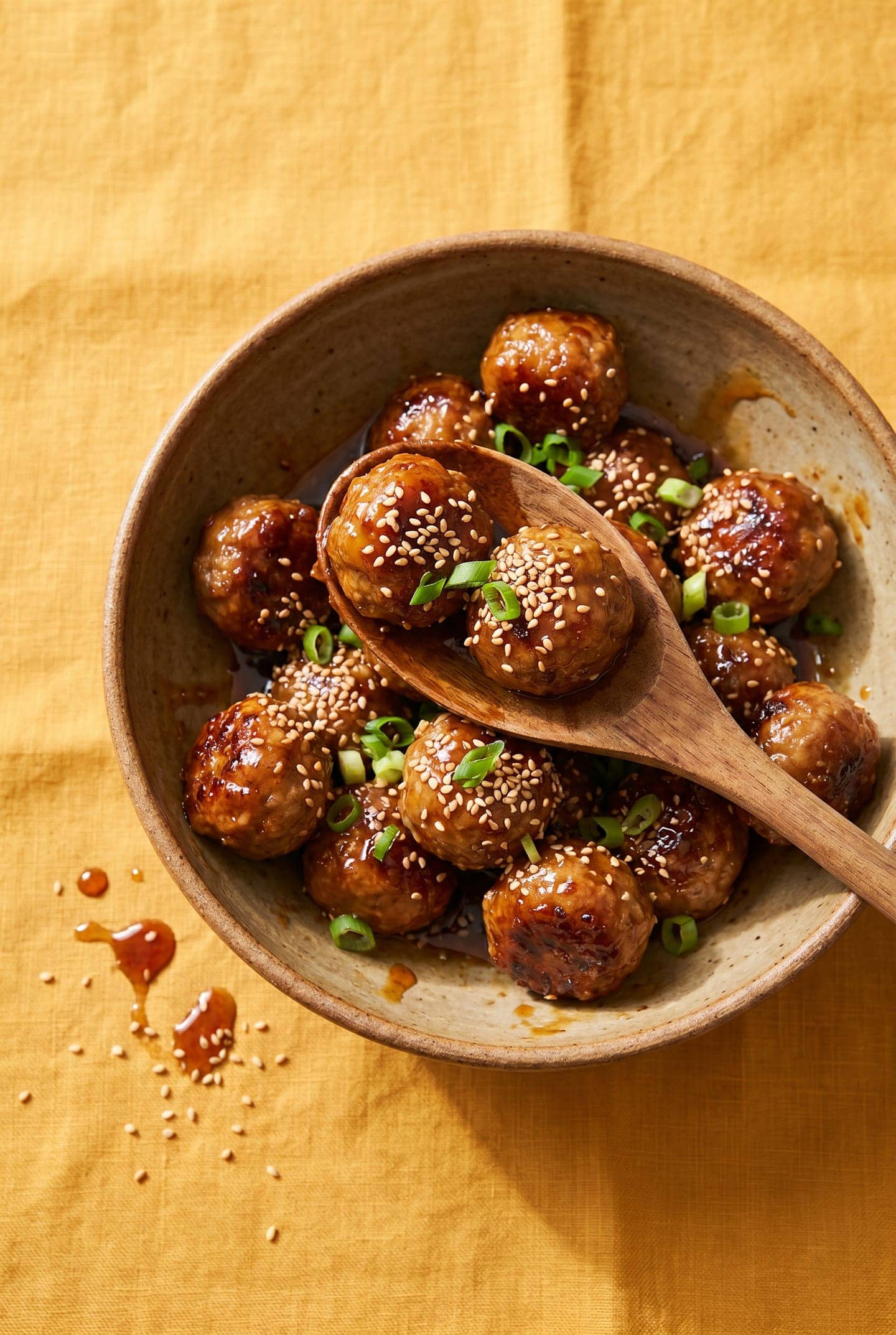 Sticky honey garlic air-fryer meatballs in a bowl with sesame and scallions